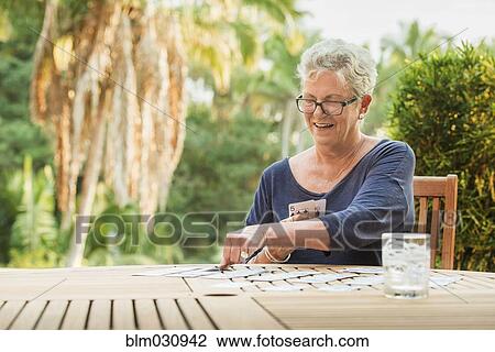Stock Image - Caucasian woman playing cards outdoors. Fotosearch