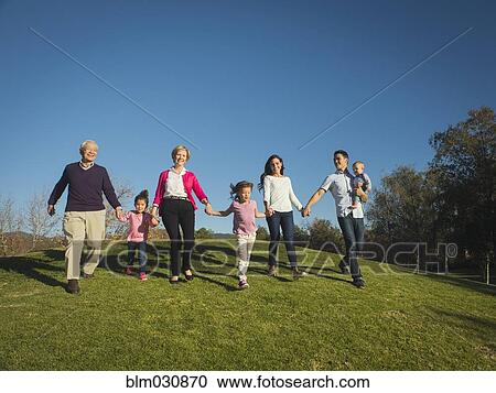 Stock Image - Family walking together in park. Fotosearch