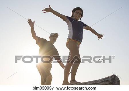Stock Photo - Father and daughter balancing on log. Fotosearch