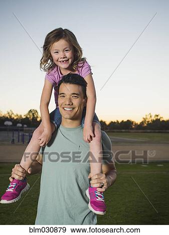 Stock Photo - Father carrying daughter on shoulders in park. Fotosearch