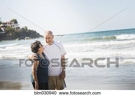 Stock Image - Hispanic couple hugging on beach. Fotosearch