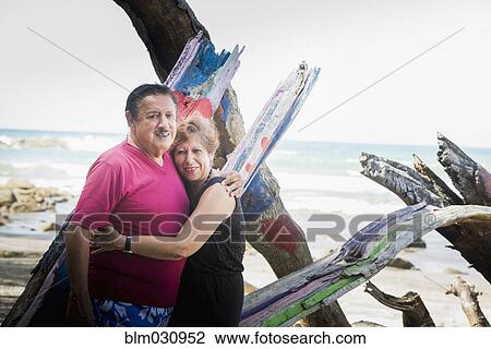 Stock Image - Hispanic couple hugging on beach. Fotosearch