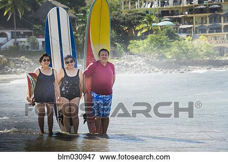 Stock Photo - Hispanic friends with surfboards on beach. Fotosearch