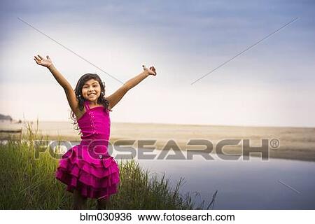 Stock Photograph - Hispanic girl cheering by still water. Fotosearch