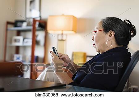 Japanese businesswoman using cell phone at desk View Large Photo Image Stock Photo - Japanese businesswoman using cell phone at desk. Fotosearch