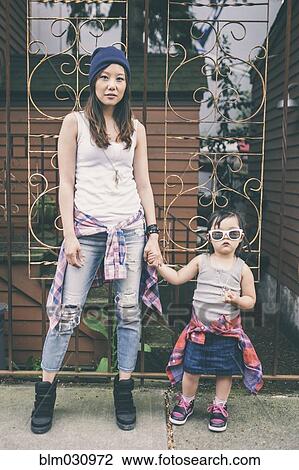 Stock Image - Korean mother and daughter holding hands on city street. Fotosearch