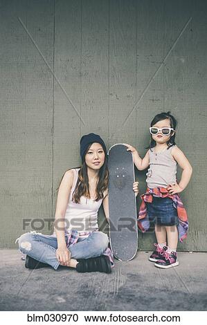 Stock Image - Korean mother and daughter posing with skateboard. Fotosearch