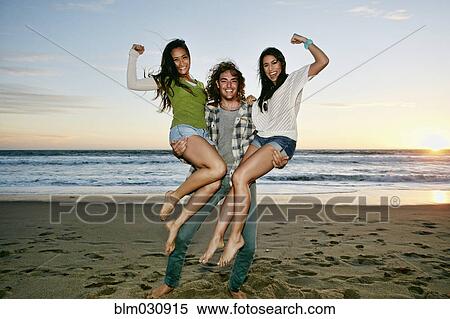 Man holding women on each arm on beach View Large Photo Image Stock Photography - Man holding women on each arm on beach. Fotosearch