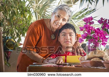 Stock Image - Older Hispanic woman hugging grandson. Fotosearch
