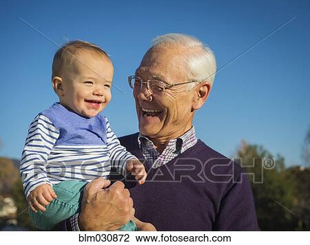 Older man holding grandson outdoors View Large Photo Image Stock Image - Older man holding grandson outdoors. Fotosearch
