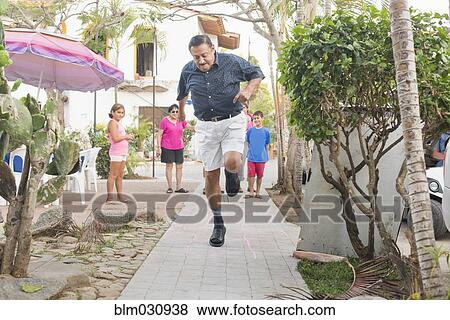 Stock Photo - Older man playing hopscotch in town square. Fotosearch