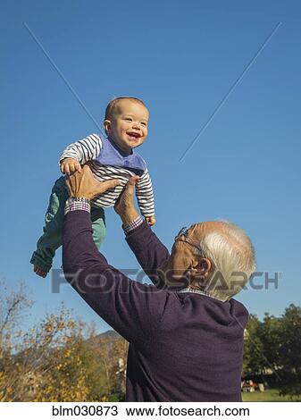 Stock Image - Older man playing with grandson outdoors. Fotosearch
