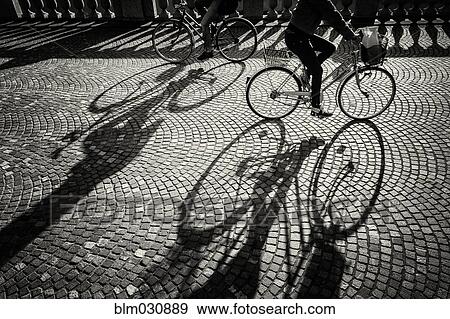Shadow of bicycles on cobblestone road View Large Photo Image Stock Photo - Shadow of bicycles on cobblestone road. Fotosearch