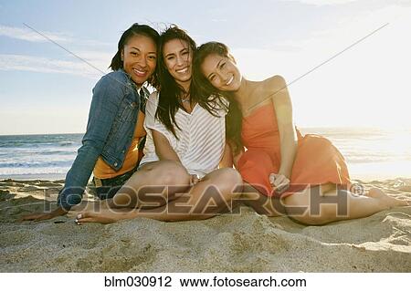Stock Image - Women smiling together on beach. Fotosearch