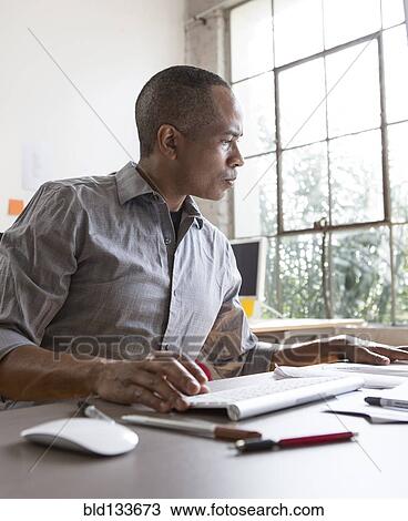 Stock Image - African American architect working in office. Fotosearch