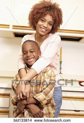 African American mother hugging son in kitchen View Large Photo Image Picture - African American mother hugging son in kitchen. Fotosearch