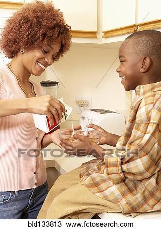 Stock Image - African American mother making son's breakfast. Fotosearch