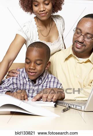 Stock Image - African American parents helping son with homework. Fotosearch