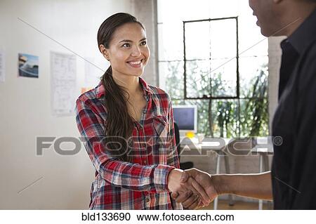 Stock Image - Architects shaking hands in office. Fotosearch