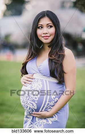 Stock Photograph - Asian woman holding her pregnant belly. Fotosearch