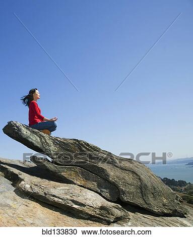 Asian woman meditating on rock formation View Large Photo Image Stock Image - Asian woman meditating on rock formation. Fotosearch