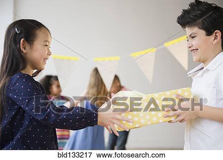 Stock Photo - Boy giving girl birthday present at party. Fotosearch