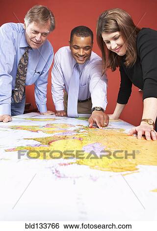 Stock Photograph - Business people examining world map. Fotosearch