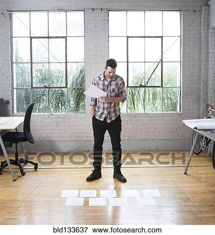 Stock Photo - Caucasian architect reading papers in office. Fotosearch