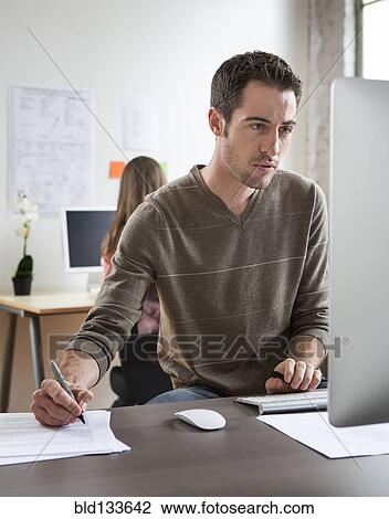 Stock Image - Caucasian architect working in office. Fotosearch