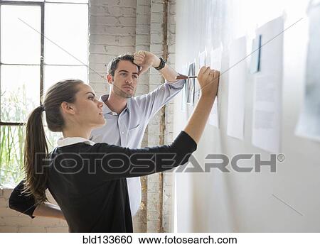 Stock Image - Caucasian architects drawing on photos in office. Fotosearch