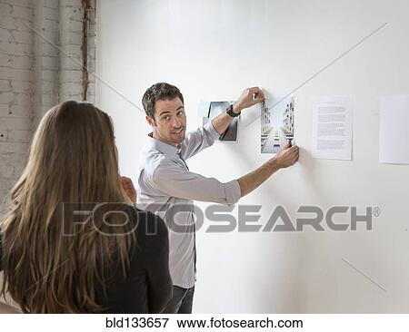 Stock Photo - Caucasian architects examining photos in office. Fotosearch