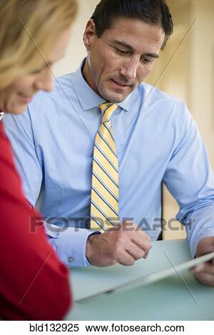 Stock Photography - Caucasian business people using digital tablet in meeting. Fotosearch