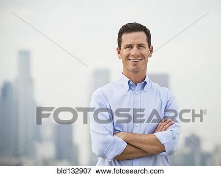 Stock Photo - Caucasian businessman standing on urban rooftop. Fotosearch