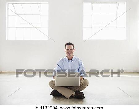Picture - Caucasian businessman using laptop in empty office. Fotosearch