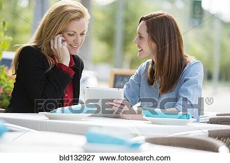 Caucasian businesswomen using digital tablet at lunch View Large Photo Image Stock Photo - Caucasian businesswomen using digital tablet at lunch. Fotosearch