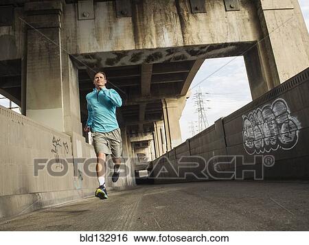Stock Photograph - Caucasian man running in urban tunnel. Fotosearch