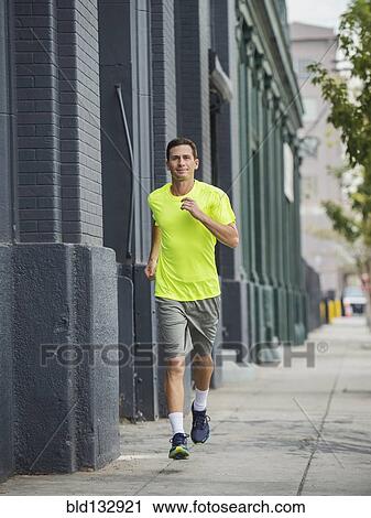 Stock Image - Caucasian man running on city street. Fotosearch