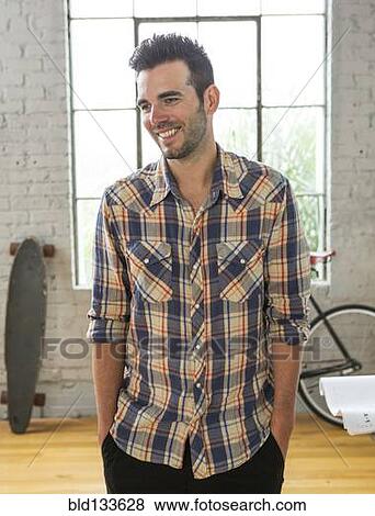 Stock Photo - Caucasian man smiling in loft. Fotosearch