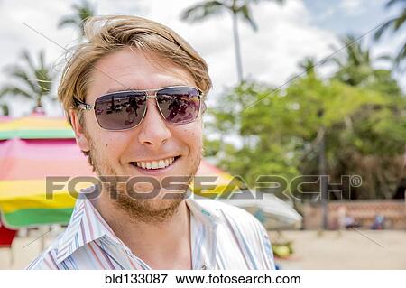 Stock Photo - Caucasian man smiling on tropical beach. Fotosearch