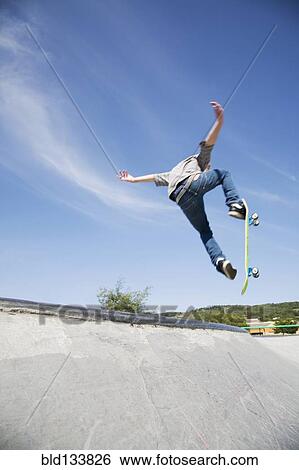 Stock Photograph - Caucasian teenage boy doing tricks in skate park. Fotosearch
