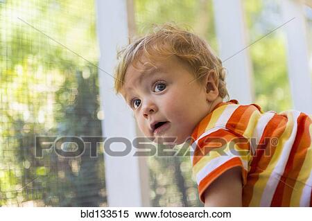 Stock Photography - Caucasian toddler peering out screen fence. Fotosearch