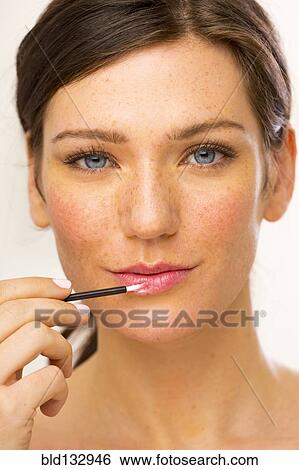 Stock Photograph - Caucasian woman applying makeup. Fotosearch