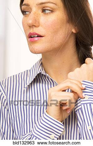 Stock Image - Caucasian woman buttoning shirt cuffs. Fotosearch