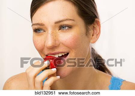 Stock Image - Caucasian woman eating strawberry. Fotosearch