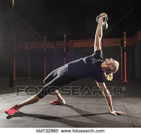 Stock Photography - Caucasian woman lifting weights in gym. Fotosearch