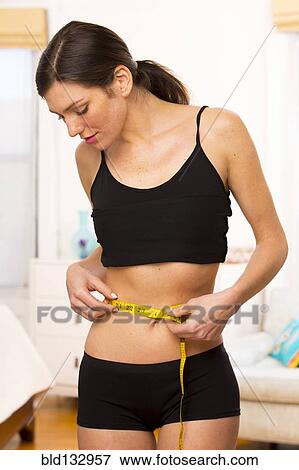 Caucasian woman measuring her waist View Large Photo Image Stock Photo - Caucasian woman measuring her waist. Fotosearch