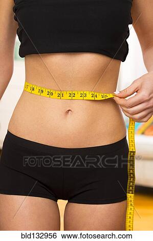 Caucasian woman measuring her waist View Large Photo Image Stock Photograph - Caucasian woman measuring her waist. Fotosearch