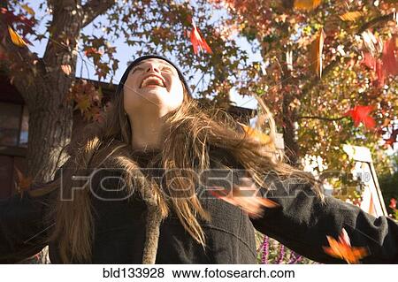 Stock Photo - Caucasian woman playing in fall leaves. Fotosearch