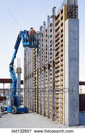 Stock Photo - Caucasian worker on boom lift at construction site. Fotosearch