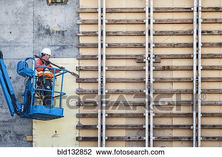 Caucasian worker on boom lift working on construction site View Large Photo Image Stock Image - Caucasian worker on boom lift working on construction site. Fotosearch